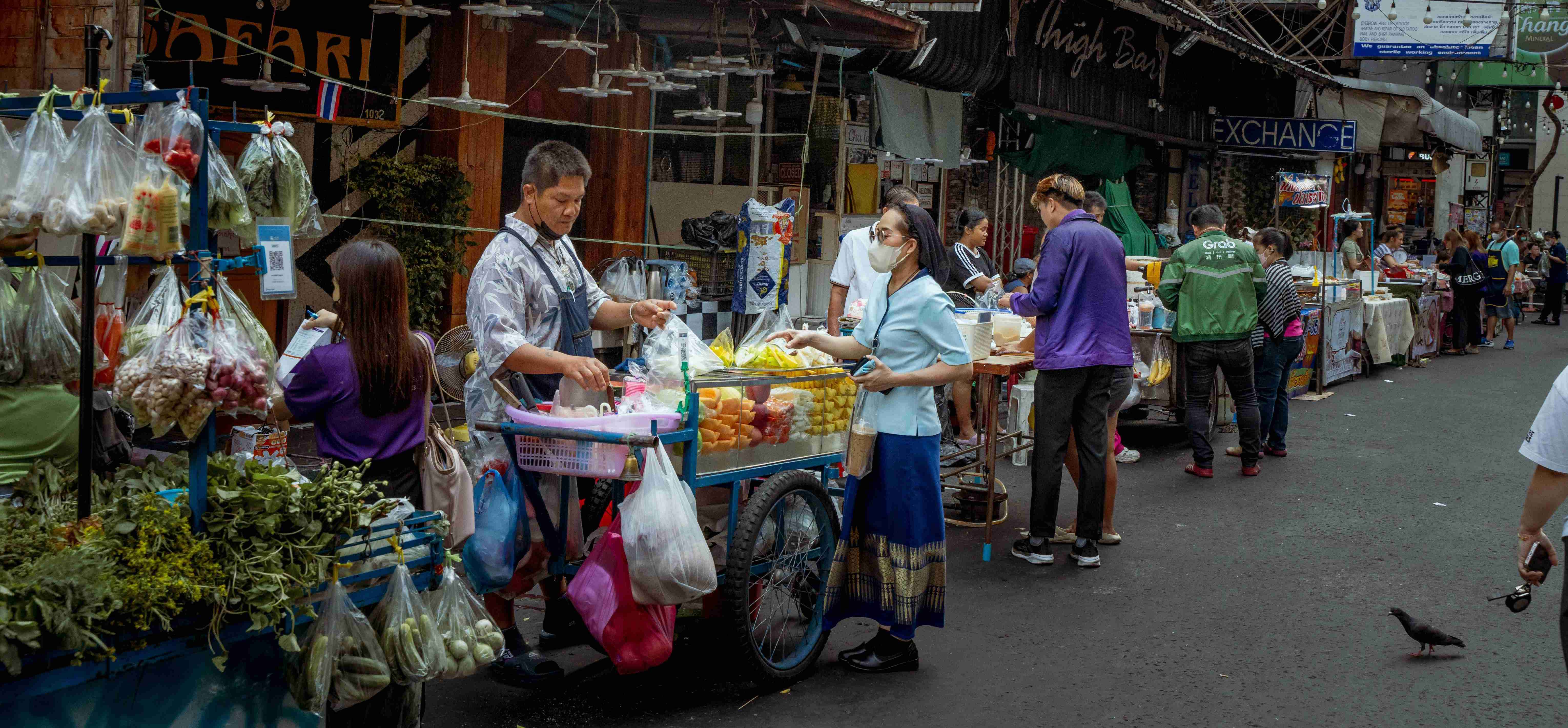 Vibrant street market with vendors and customers making transactions